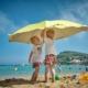 Two boys on the beach putting up an umbrella