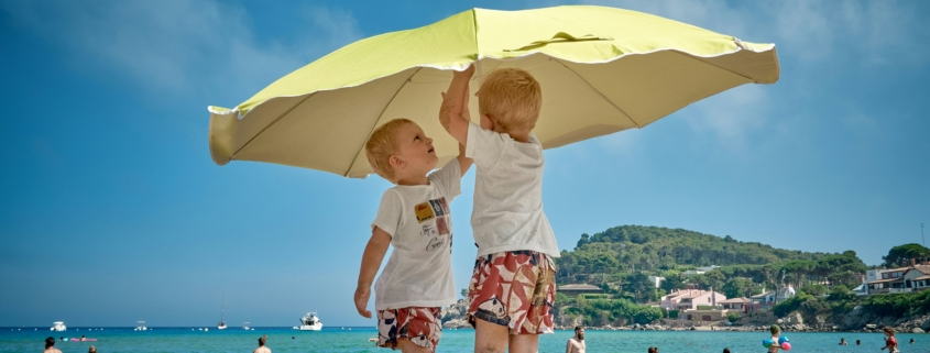 Two boys on the beach putting up an umbrella